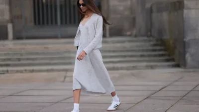 Jill Asemota seen wearing black vintage sunglasses, Dorothee Schumacher grey wool knit long dress, matching Dorothee Schumacher grey wool knit cardigan jacket, white cotton socks, Adidas white leather Samba sneakers, on November 04, 2023 in Berlin, Germany.