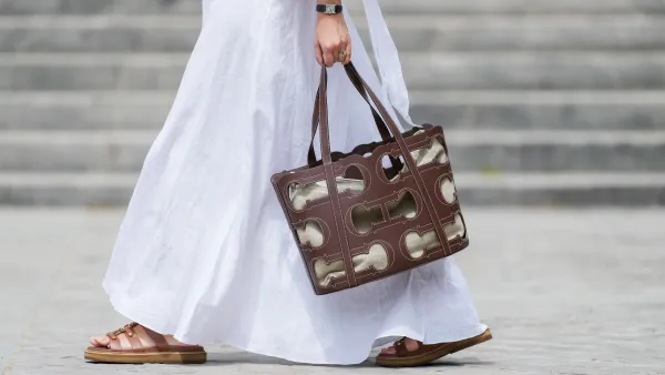 Gabriella Berdugo wears a Cartier watch, a white linen gathered dress from kalita, a brown summer bag from Carolina Herrera in brown leather, brown leather sandals from Celine, during a street style fashion photo session, on May 12, 2024 in Paris, France.