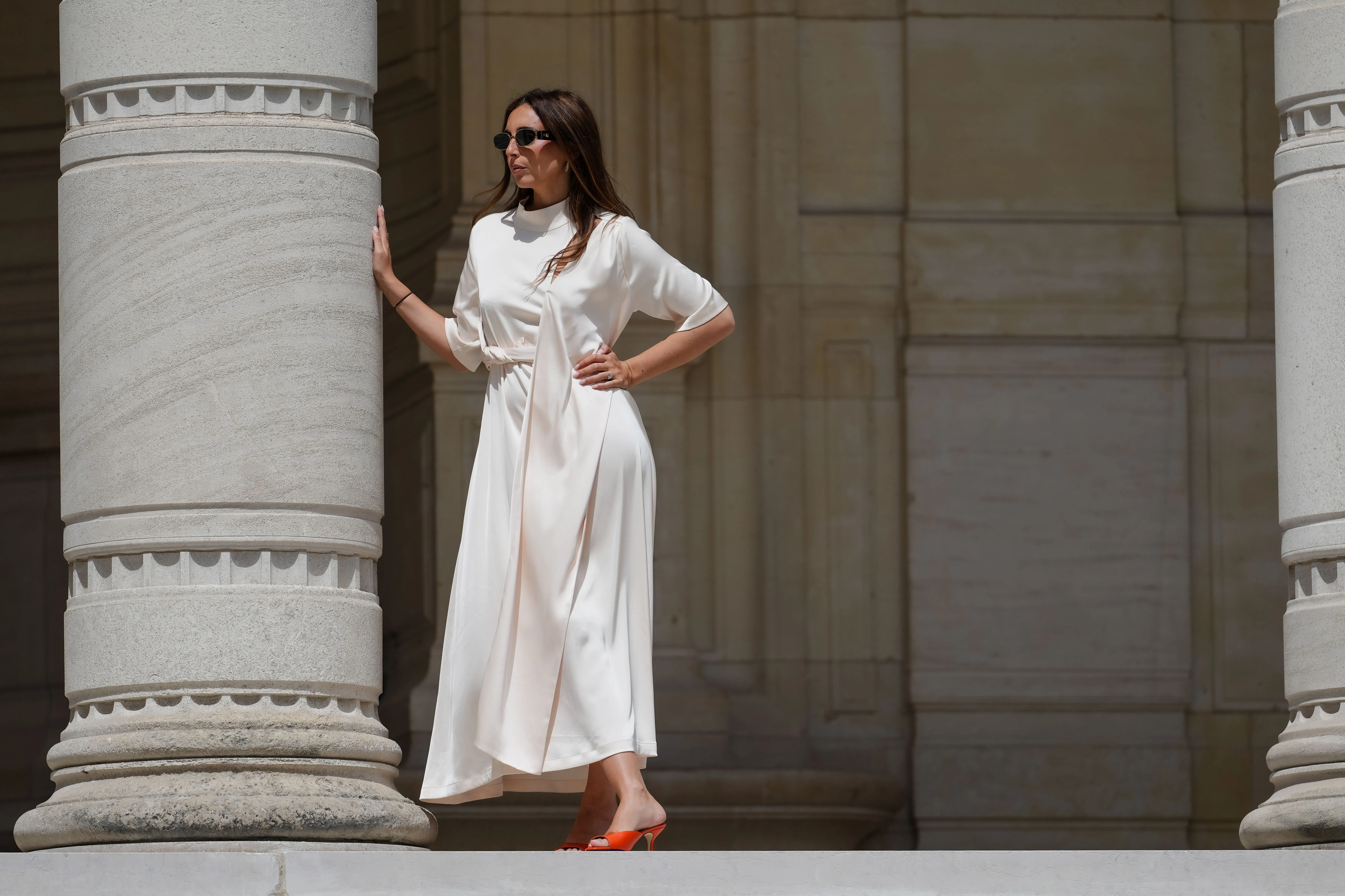 Gabriella Berdugo wears sunglasses, a white long gathered dress with a scarf from Gestuz, red kitten heels mule shoes with open toe from Age of Innocence, during a street style fashion photo session, on May 16, 2024 in Paris, France.