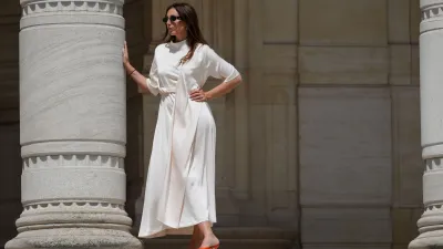 Gabriella Berdugo wears sunglasses, a white long gathered dress with a scarf from Gestuz, red kitten heels mule shoes with open toe from Age of Innocence, during a street style fashion photo session, on May 16, 2024 in Paris, France.