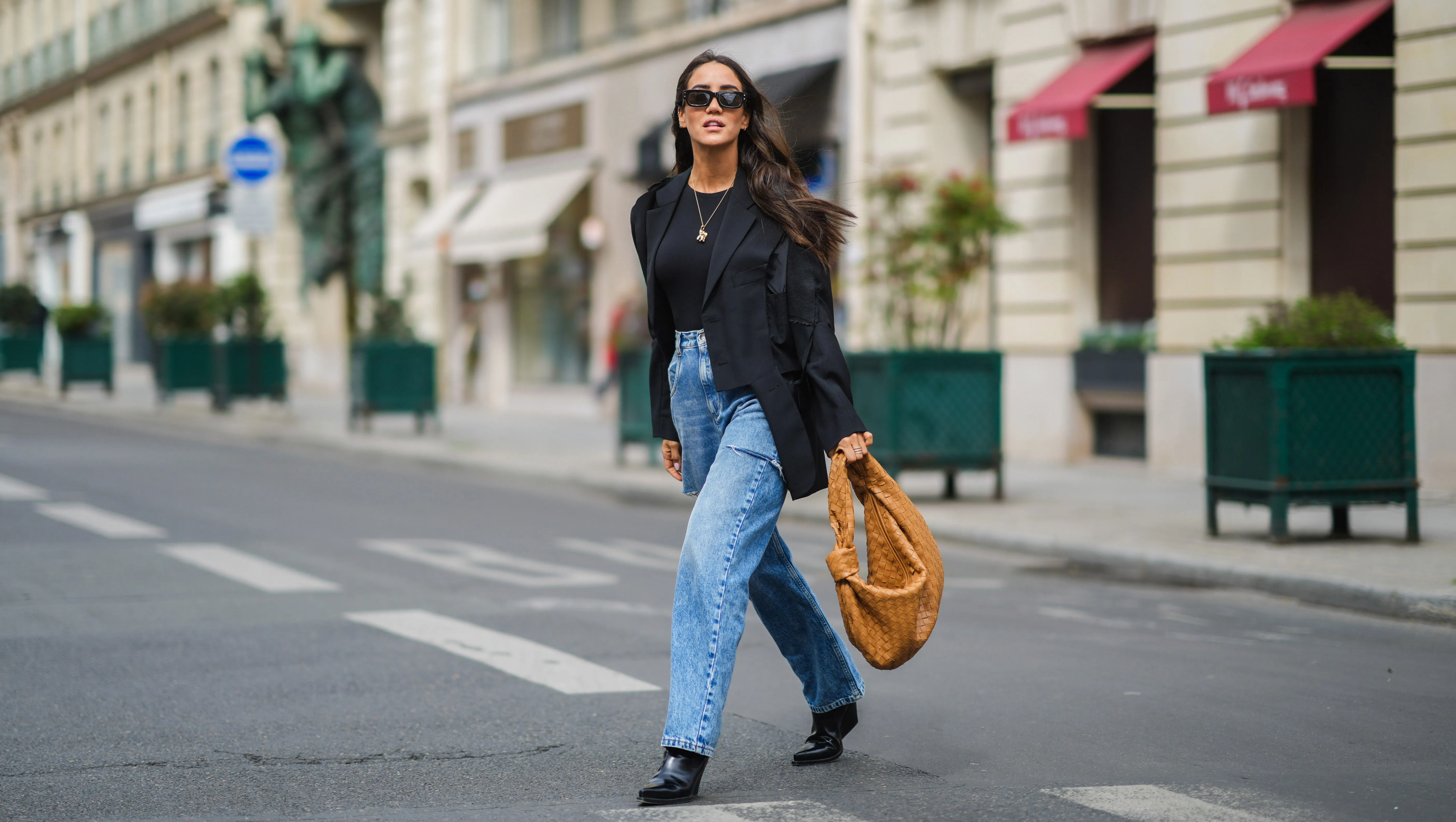 PARIS, FRANCE - APRIL 29: Tamara Kalinic wears black Sestini sunglasses, gold earrings, a black t-shirt, a black oversized ripped Margiela blazer jacket, a gold ring, blue faded denim oversized ripped Margiela jeans pants, a brown shiny leather braided Jodie Petit Bottega Veneta handbag, black shiny leather pointed heels Bottega Veneta ankle boots, on April 29, 2021 in Paris, France. (Photo by Edward Berthelot/Getty Images)