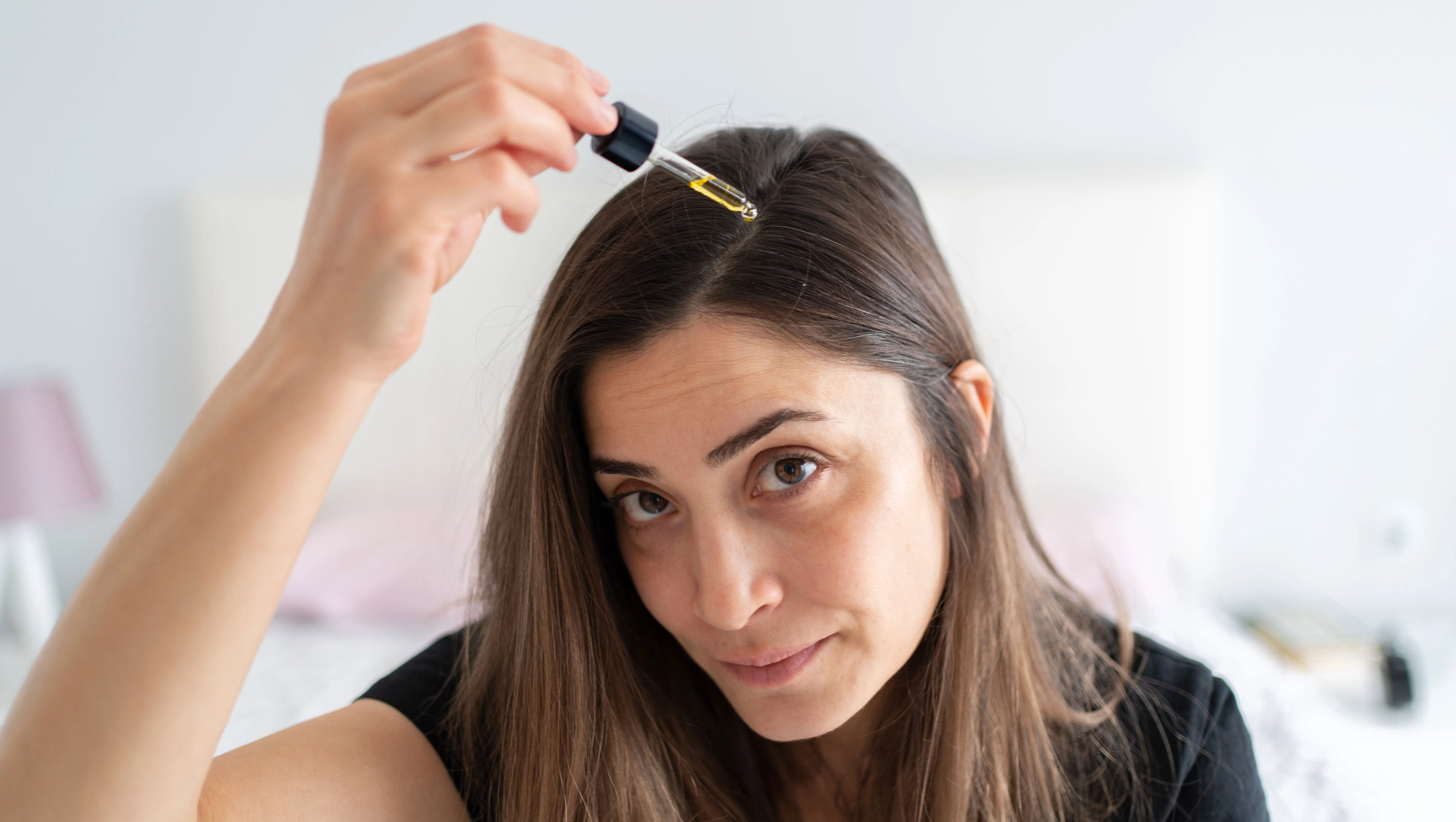 Woman Applying Hair Serum To Her Hair