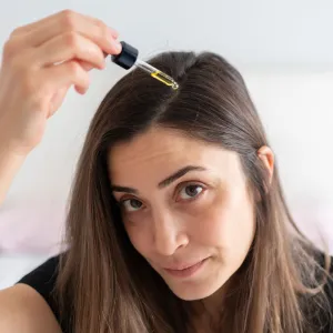Woman Applying Hair Serum To Her Hair