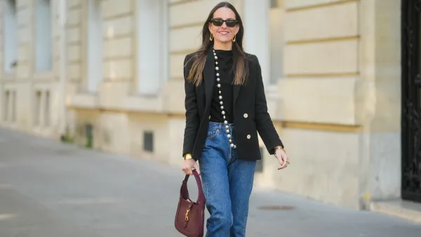 PARIS, FRANCE - APRIL 09: Alba Garavito Torre wears long straight brown hair styled with a center part. Black rectangular sunglasses are styled with large gold geometric earrings. A black T-shirt is layered under a tailored black double-breasted blazer with gold buttons by Sandro. A long strand of oversized pearls worn as a necklace by Sempiterno Paris is draped down the front. Classic blue Levi’s 5015 straight-leg jeans are worn with the hem grazing the top of the shoe. A burgundy leather Jackie bag by Gucci is carried. Full body shot, during a street style fashion photo session, on April 09, 2025 in Paris, France. (Photo by Edward Berthelot/Getty Images)