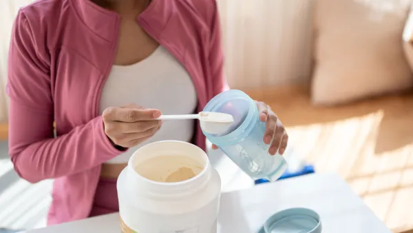 A healthy and fit Asian woman in sportswear making her protein shake after a workout at home. - stock photo