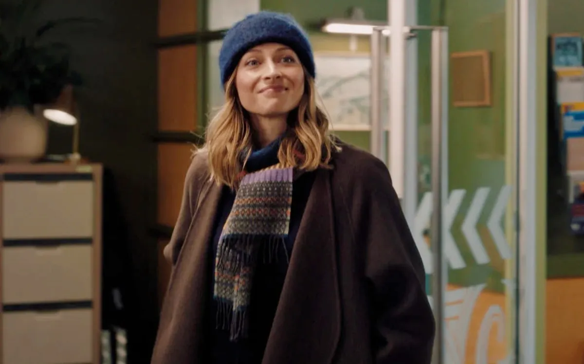 A woman in a knit hat smiles in A Remarkable Place to Die.