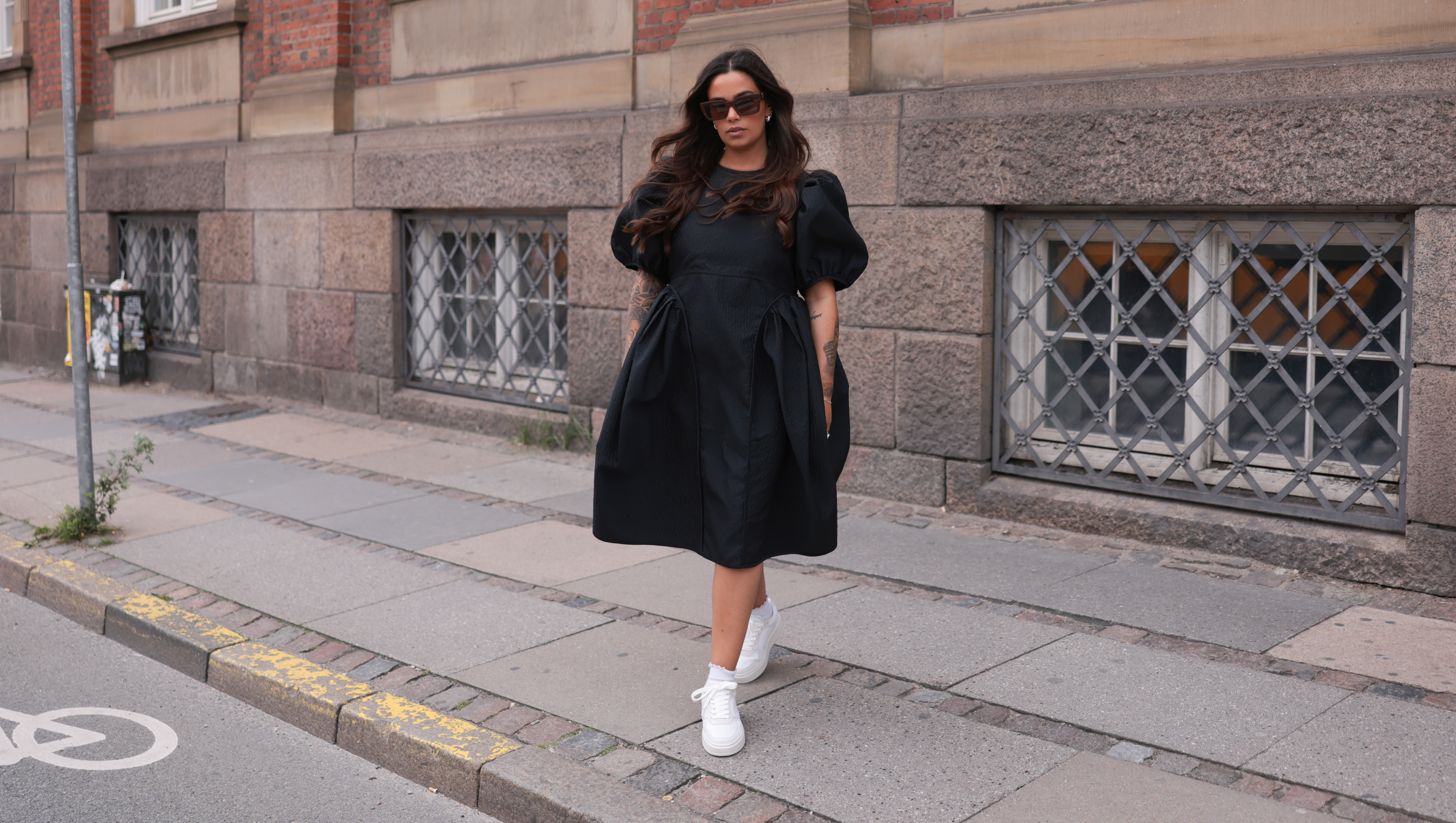 COPENHAGEN, DENMARK - AUGUST 10: Naomi Anwer seen wearing black sunglasses, black short dress, white socks and Copenhagen Studios CPH1 Vitello Off White leather sneaker, on August 10, 2023 in Copenhagen, Denmark. (Photo by Jeremy Moeller/Getty Images for The Wants Social / Copenhagen Studios)
