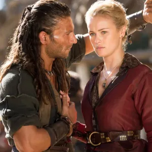 A pirate stands in front of a woman in Black Sails.