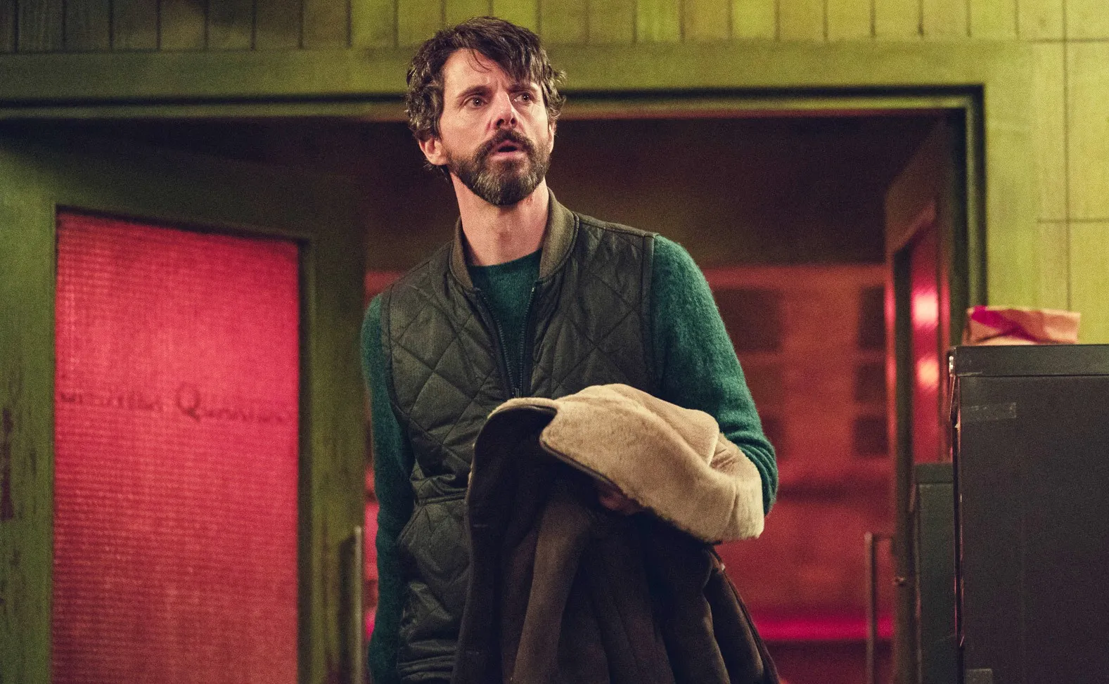 A man holds his coat in Dept. Q.