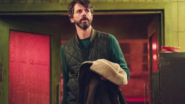 A man holds his coat in Dept. Q.