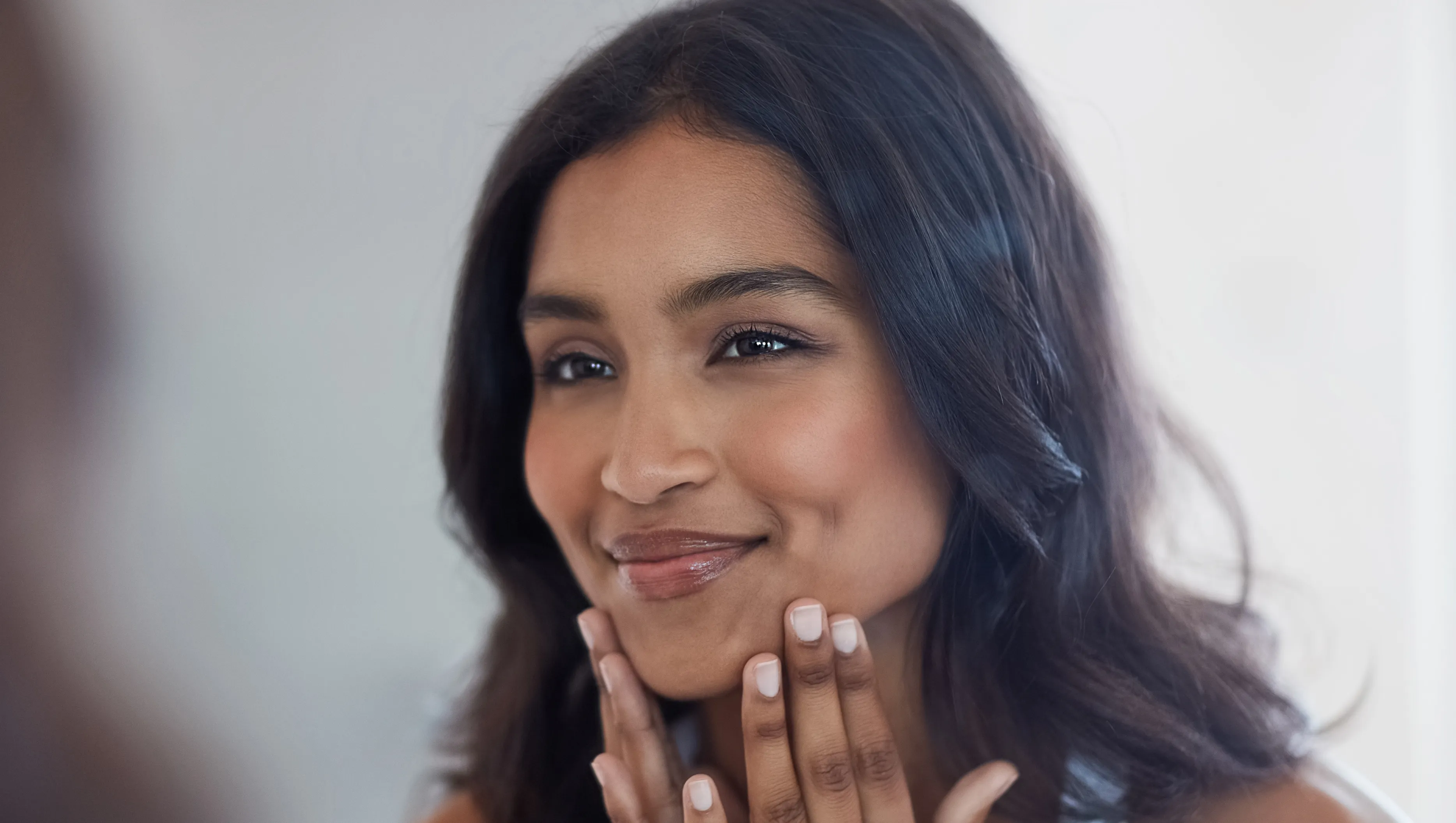 Shot of a beautiful young woman admiring herself in the mirror at home