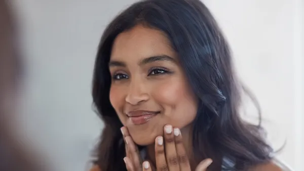 Shot of a beautiful young woman admiring herself in the mirror at home