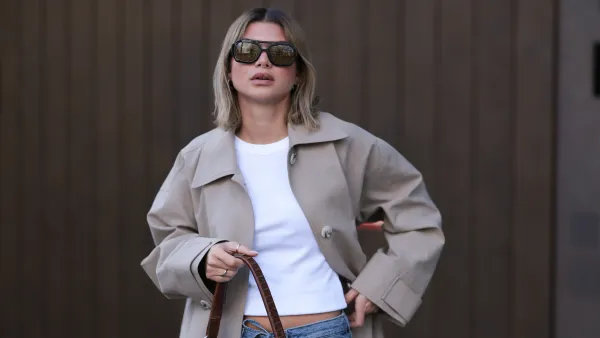 BERLIN, GERMANY - APRIL 01: Sophia Geiss seen wearing Vehla Eyewear black / brown dark sunglasses, Drykorn white cotton basic casual cropped top, Meotine beige oversized trench coat adds effortless elegance, COS blue denim oversized, loose-fitting, wide-leg jeans with a drawstring waist enhance the relaxed vibe and a brown suede leather vintage bag complements the western aesthetic, on April 01, 2025 in Berlin, Germany. (Photo by Jeremy Moeller/Getty Images)