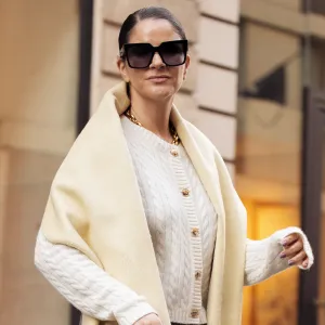 PARIS, FRANCE - MARCH 06: Gili Biegun wears grey pants, white knitted top with long sleeves, and pale yellow long wide scarf, balck leather bag and sunglasses during the Womenswear Fall/Winter 2025/2026 as part of Paris Fashion Week on March 06, 2025 in Paris, France. (Photo by Raimonda Kulikauskiene/Getty Images)