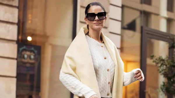 PARIS, FRANCE - MARCH 06: Gili Biegun wears grey pants, white knitted top with long sleeves, and pale yellow long wide scarf, balck leather bag and sunglasses during the Womenswear Fall/Winter 2025/2026 as part of Paris Fashion Week on March 06, 2025 in Paris, France. (Photo by Raimonda Kulikauskiene/Getty Images)