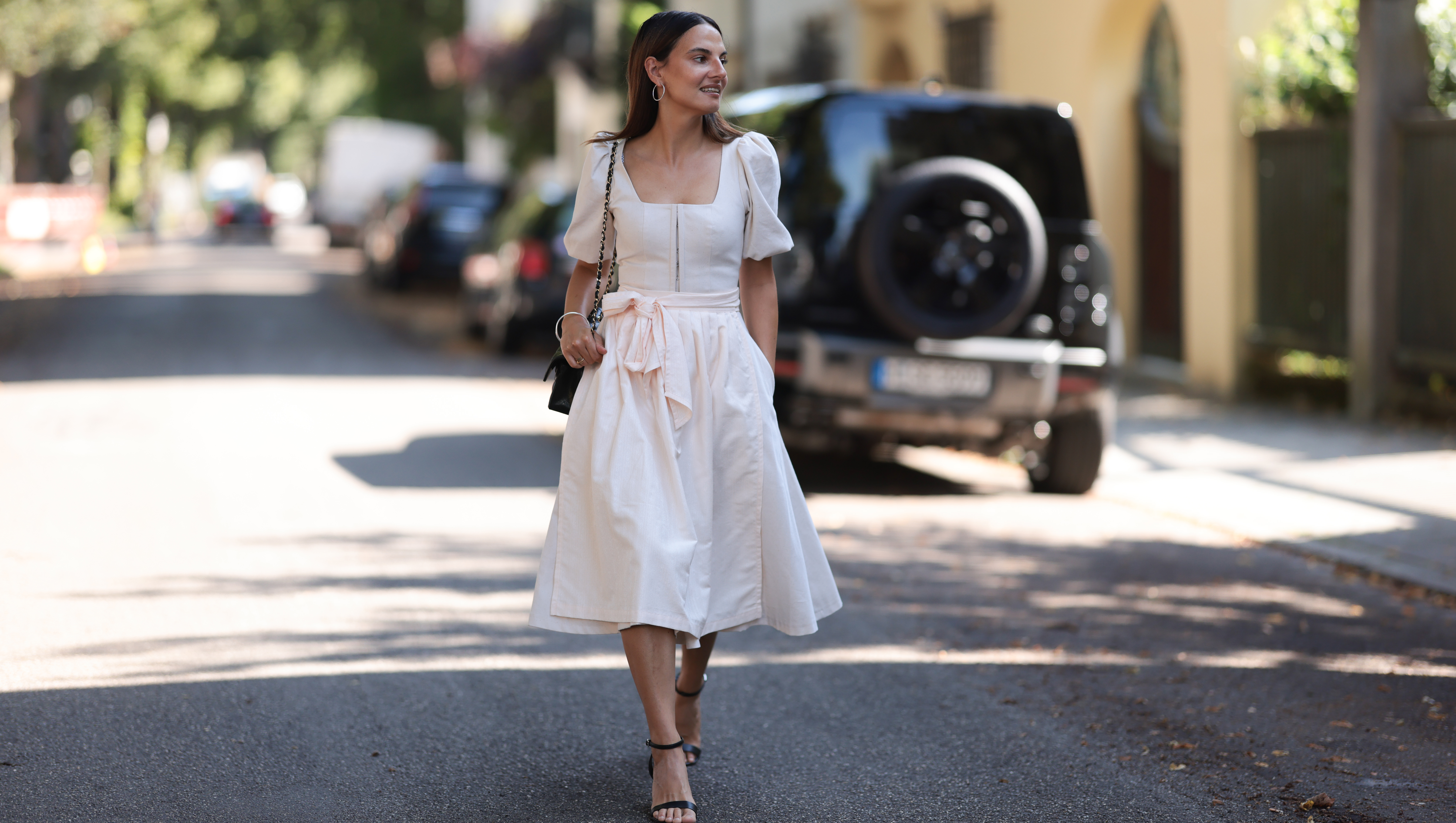 MUNICH, GERMANY - AUGUST 15: Anna Winter seen wearing silver hoop earrings, Cocovero creamy white dirndl / short dress, Chanel black leather bag, silver bangle and black leather heels, on August 15, 2024 in Munich, Germany. (Photo by Jeremy Moeller/Getty Images)