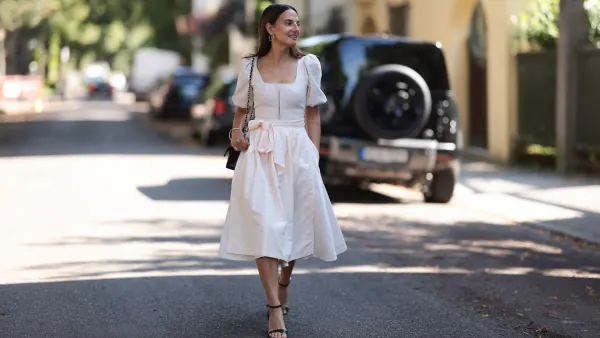 MUNICH, GERMANY - AUGUST 15: Anna Winter seen wearing silver hoop earrings, Cocovero creamy white dirndl / short dress, Chanel black leather bag, silver bangle and black leather heels, on August 15, 2024 in Munich, Germany. (Photo by Jeremy Moeller/Getty Images)