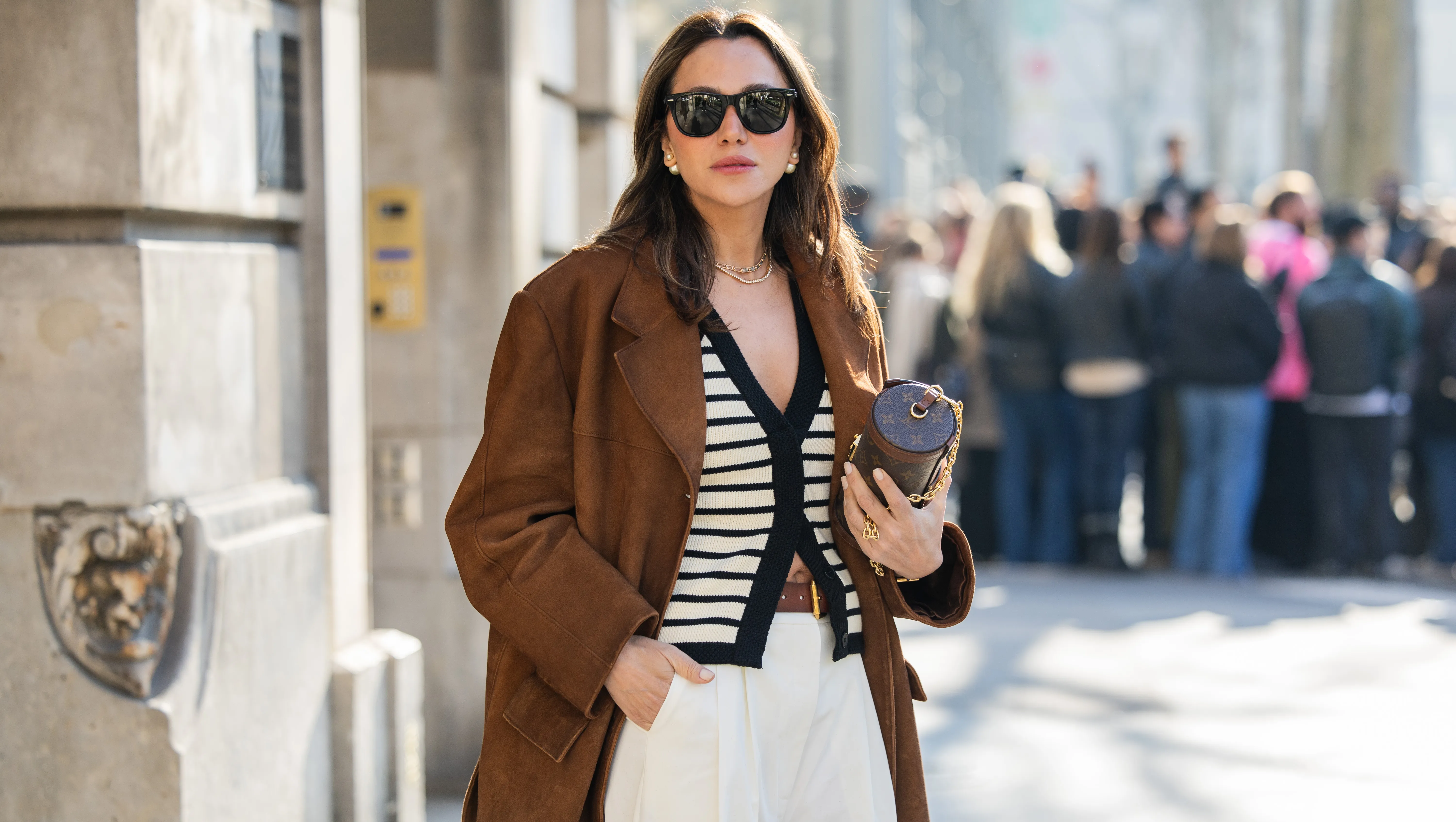 PARIS, FRANCE - MARCH 05: Yasemin Ögün wears brown suede jacket, Louis Vuitton bag, striped black white cardigan, creme white pants, sunglasses outside Courrèges during the Womenswear Fall/Winter 2025/2026 as part of Paris Fashion Week on March 05, 2025 in Paris, France. (Photo by Christian Vierig/Getty Images)