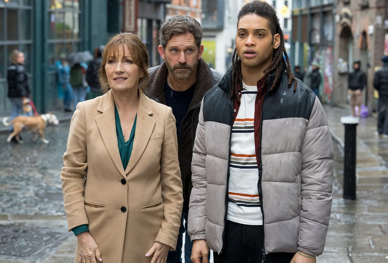 Three people stand in the street in Harry Wild.
