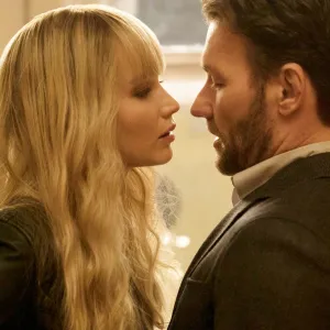 A woman leans near a man in Red Sparrow.