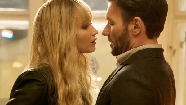 A woman leans near a man in Red Sparrow.