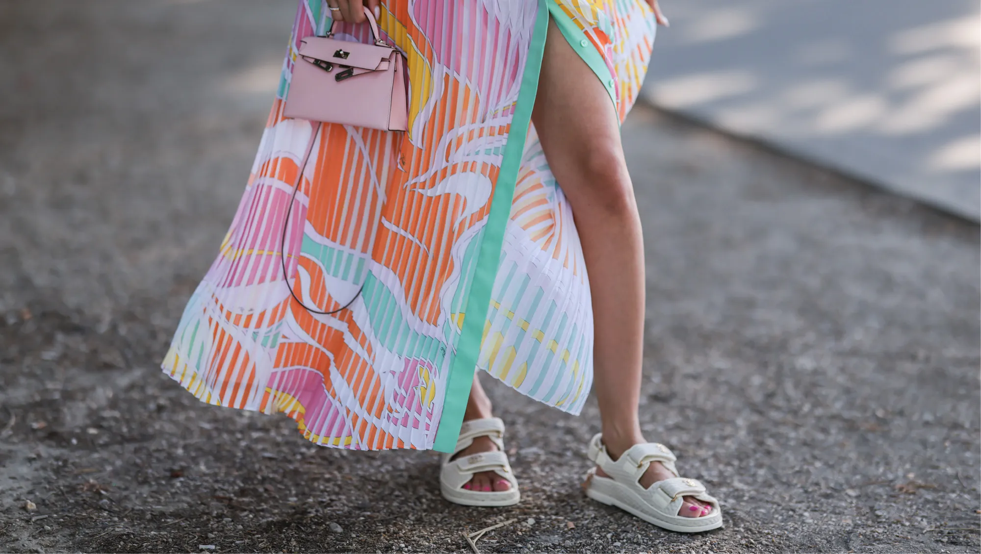 Mandy Bork seen wearing a colorful buttoned / pleated / sleeveless long dress from Emilio Pucci, a pale pink leather Hermes Kelly mini bag, gold diamond Cartier Love bracelet, a gold Cartier Juste Un Clou bracelet and white creme sandals from Chanel, during Paris Fashion Week - Haute Couture Fall Winter 2022 2023, on July 06, 2022 in Paris, France.