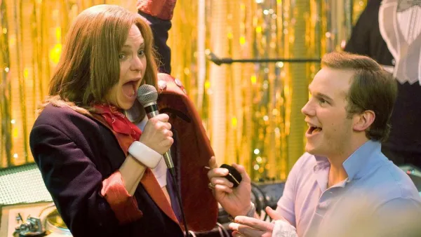 A guy looks at a girl singing in Take Me Replica Luxury Handbag Tonight.