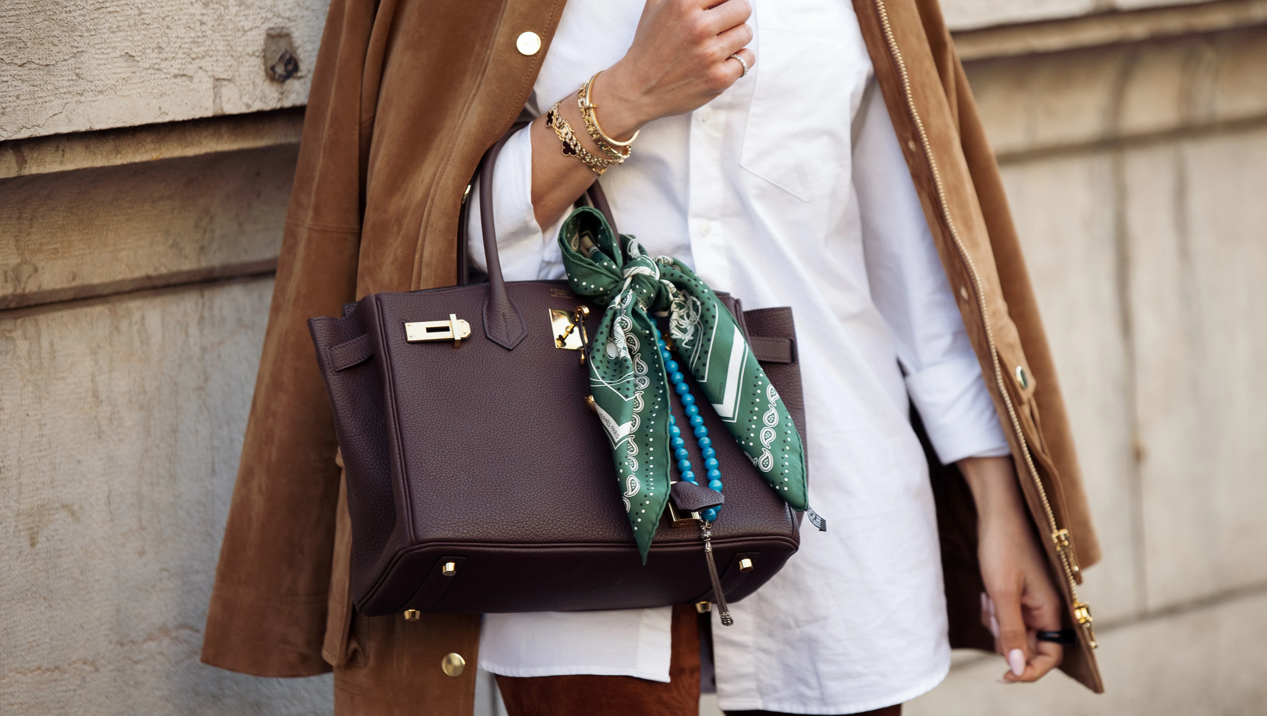PARIS, FRANCE - MARCH 08: A guest wears white shirt, brown pants, brown suede jacket and brown Hermes bag with a green and white silk neck scarf outside the Hermes fashion show during the Womenswear Fall/Winter 2025/2026 as part of Paris Fashion Week on March 08, 2025 in Paris, France. (Photo by Raimonda Kulikauskiene/Getty Images)