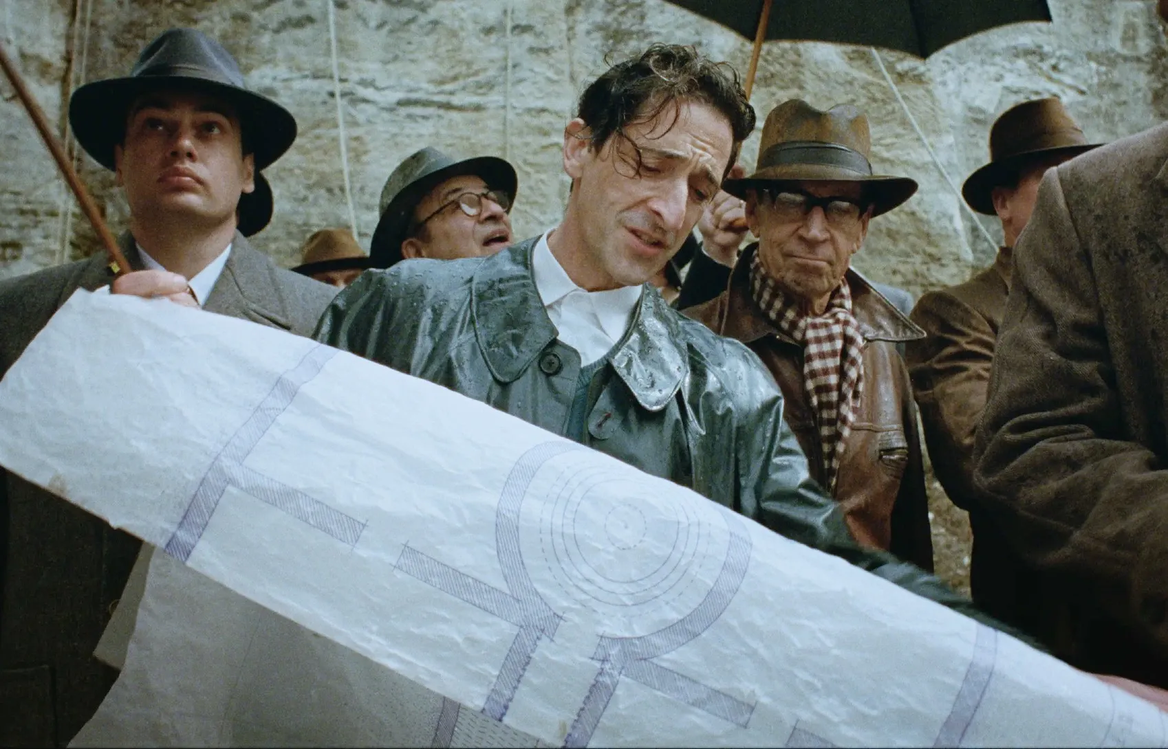 A man looks at a building plan in 'The Brutalist.'