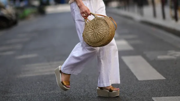 PARIS, FRANCE - MAY 10: Maria Rosaria Rizzo wears a white latte t-shirt with fringed borders, a beige wickers handbag from Guerlain, a gold large bracelet, gold rings, high waist white wide legs linen pants, during a street style fashion photo session, on May 10, 2022 in Paris, France. (Photo by Edward Berthelot/Getty Images)