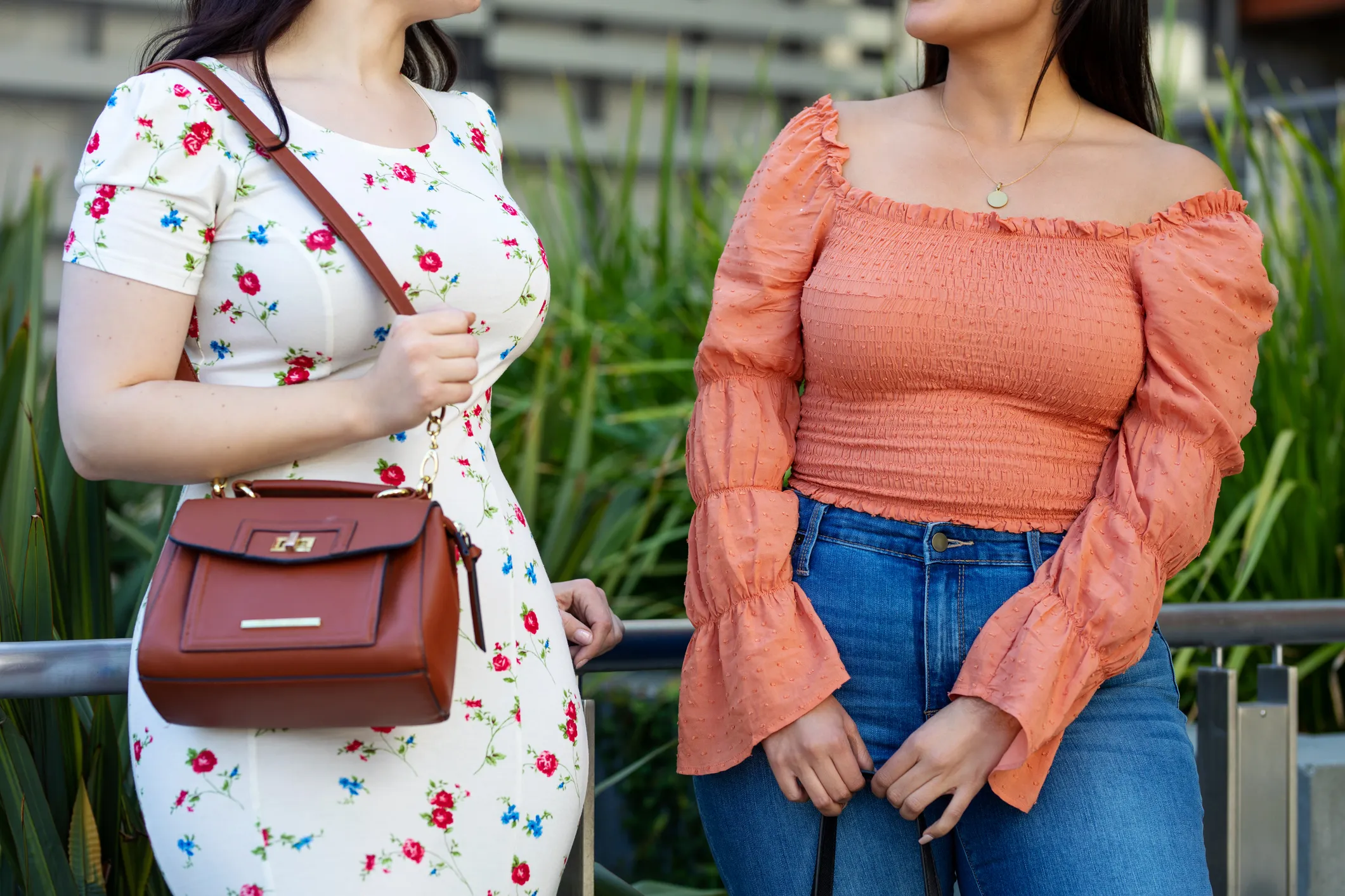Cropped shot of two females friends standing outdoors and talking. Women in casual clothing chatting in the city.