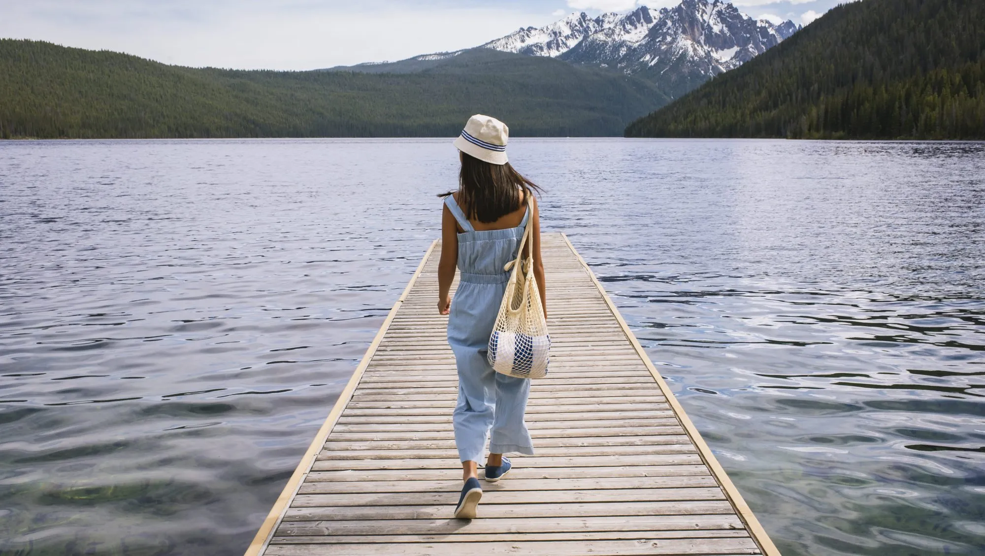 Young woman walking on dock at mountain lake