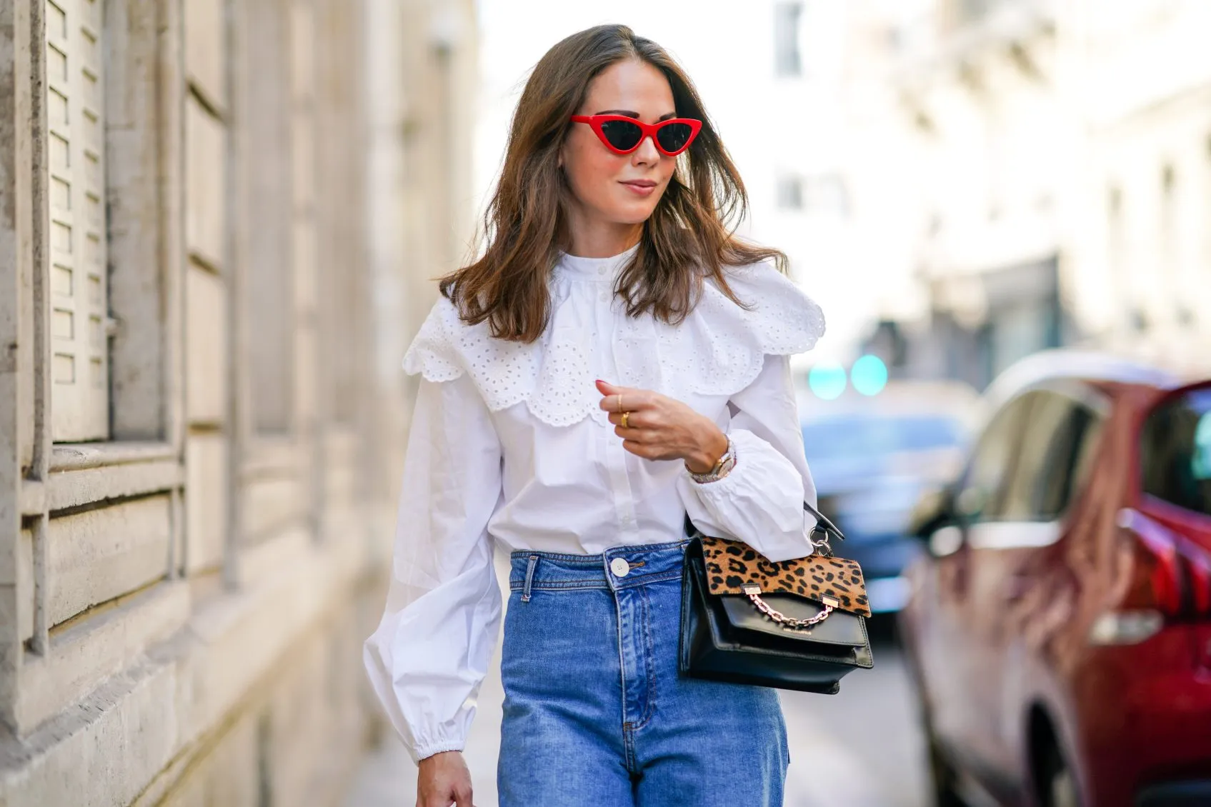 Therese Hellström wears red Celine sunglasses, a white shirt / blouse from H&M with large ruffled collar, a black leather Karl Lagerfeld bag with a chain and brown leopard print, blue denim flared jeans from Zara, on September 15, 2020 in Paris, France.