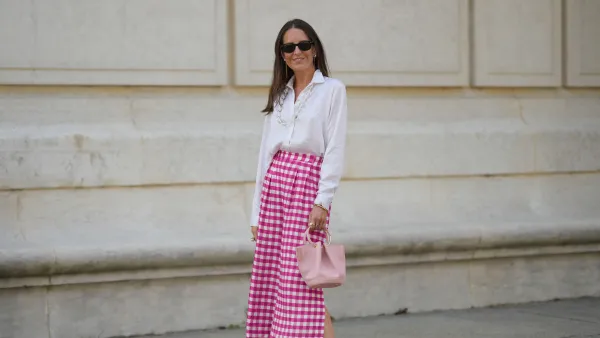 PARIS, FRANCE - JUNE 06: Alba Garavito Torre wears black sunglasses from Ray Ban, white pearl and gold chain pendant earrings, a transparent large pearls long necklace, a white shirt, pink and white checkered print pattern midi pants from Frambuã, gold bracelets, a pale pink matte leather handbag from Saonara Brand, white latte matte shiny leather block heels mules from Jonak, during a street style fashion photo session, on June 06, 2023 in Paris, France. (Photo by Edward Berthelot/Getty Images)