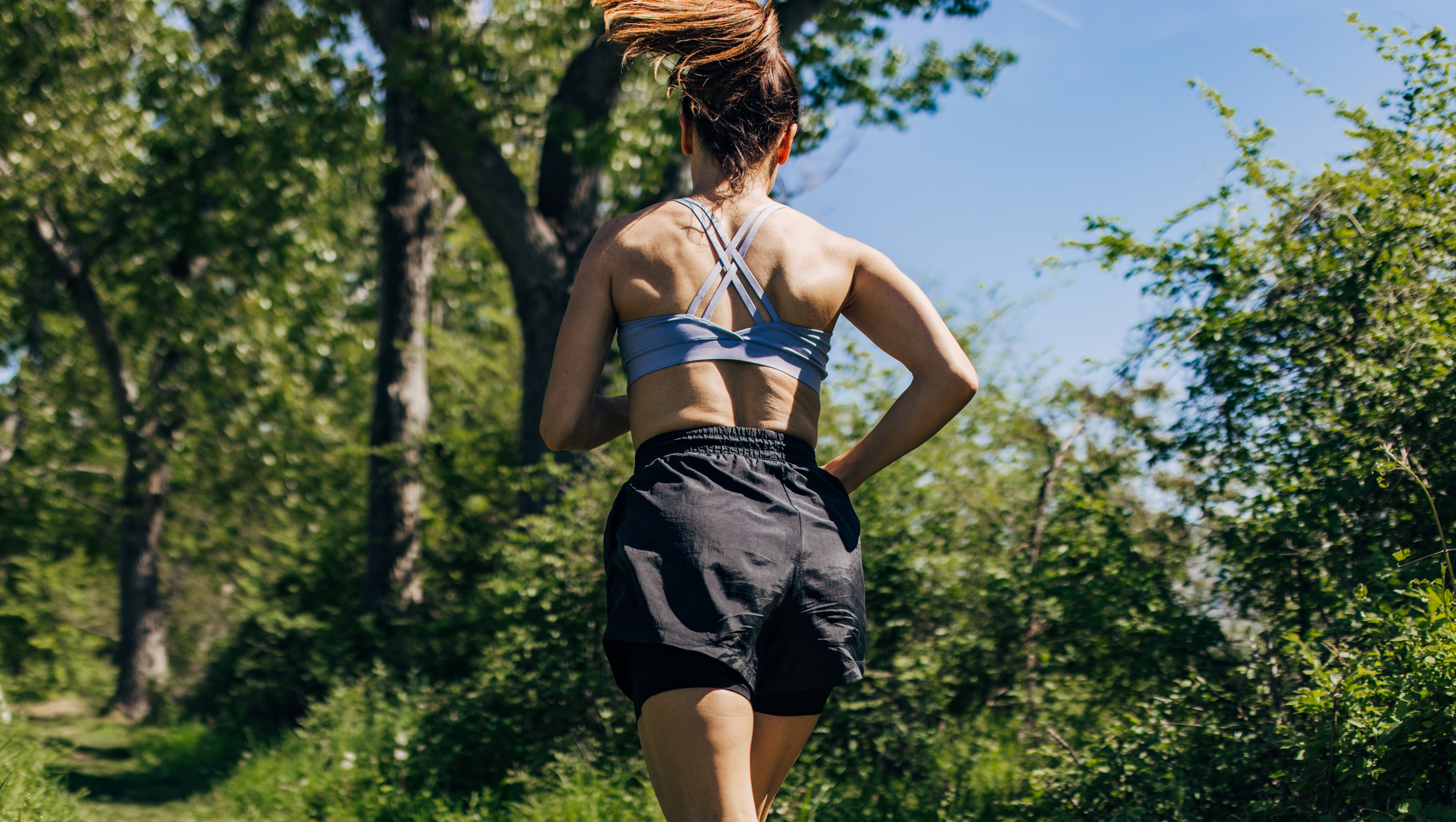 Mid adult woman running in the forest on a sunny day
