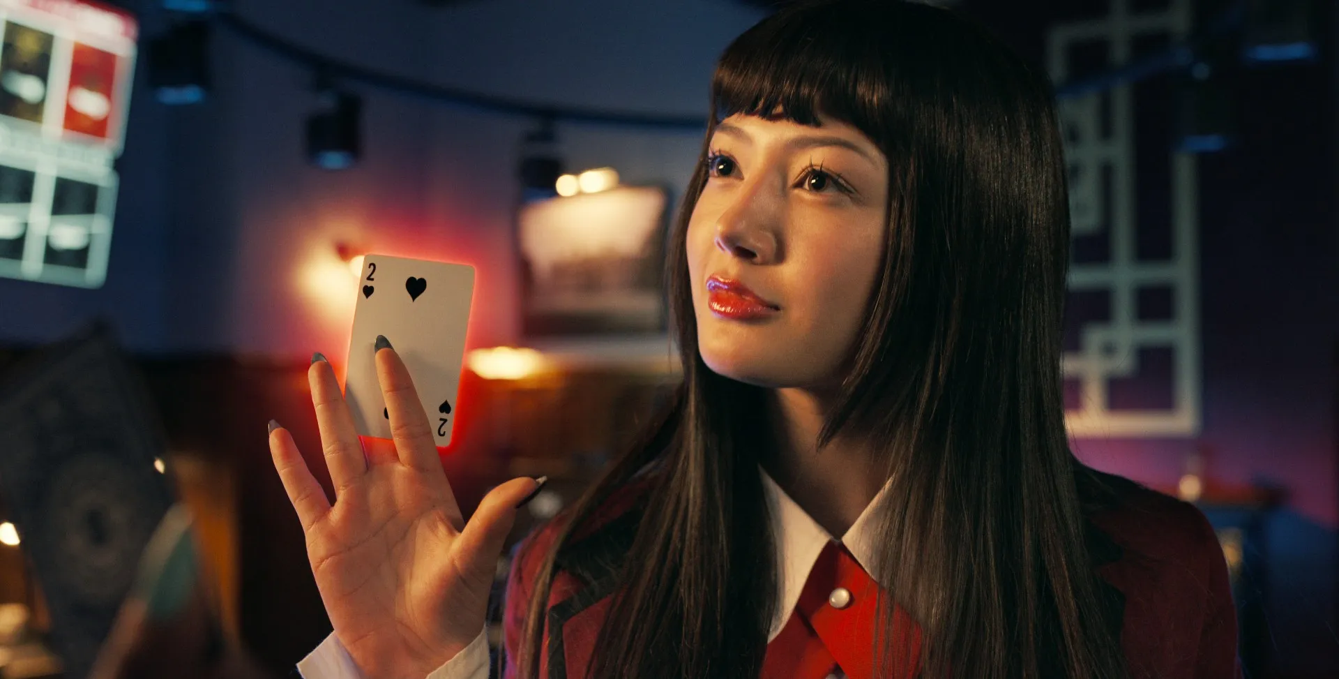 A woman holds a card in 'Bet.'