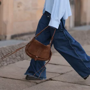 BERLIN, GERMANY - APRIL 22: Sophia Geiss is seen wearing two different-sized silver hoop earrings, oval brown glasses from Corlin, a silver nose ring, an oversized light blue shirt from Drykorn, wide-leg jeans with orange decorative seams from Closed, a brown vintage suede bag, and dark brown leather boots with chunky soles from Miista on April 22, 2025 in Berlin, Germany. (Photo by Jeremy Moeller/Getty Images)