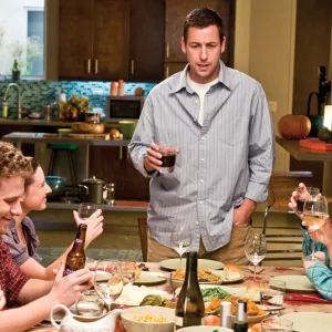 A man stands at a crowded table in 'Funny People.'