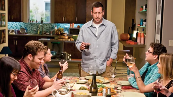 A man stands at a crowded table in 'Funny People.'