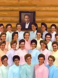 A large group of women, all dressed identically, surround a photo of FLDS leader Warren Jeffs in 'Keep Sweet: Pray and Obey.'