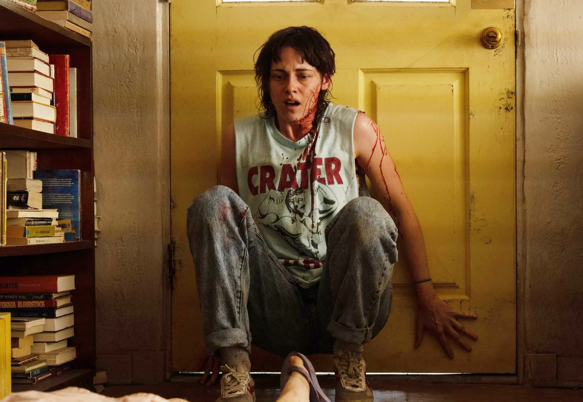 A woman leans on a door in 'Love Lies Bleeding.'