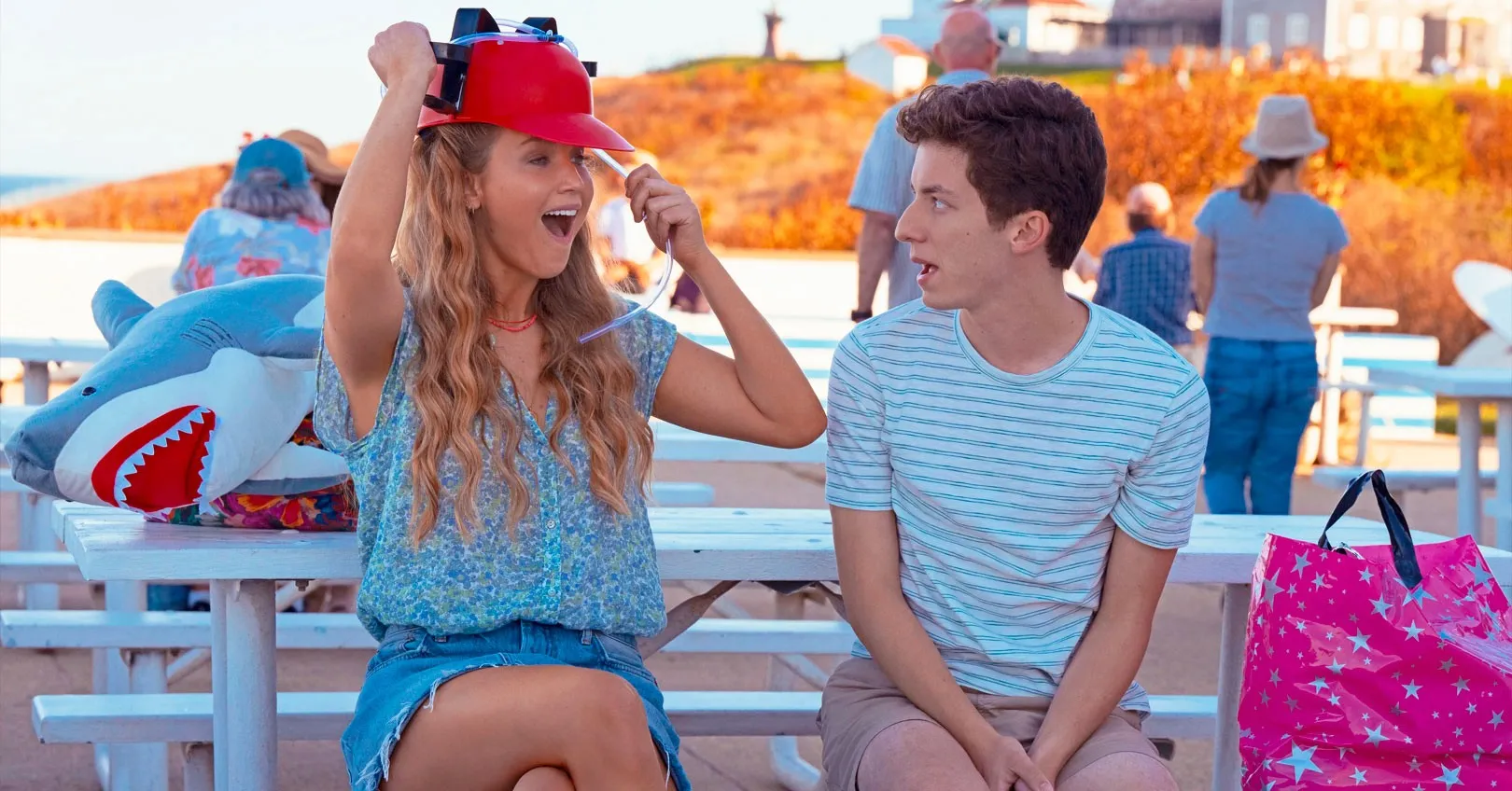 A woman puts on a red hat as a teenage boy watches in 'No Hard Feelings.'