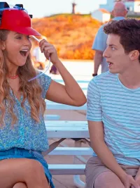 A woman puts on a red hat as a teenage boy watches in 'No Hard Feelings.'