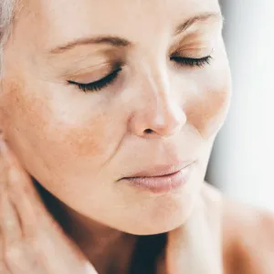 Older woman touching her skin in the mirror