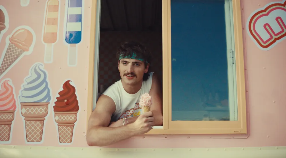 Benson Boone holding an ice cream cone in his "Mr. Electric Blue" music video