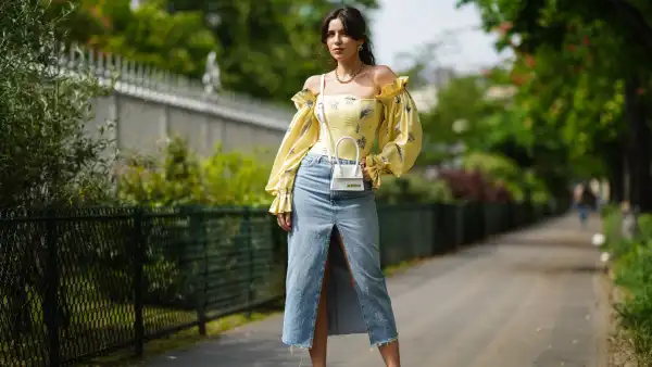 PARIS, FRANCE - APRIL 28: Ketevan Giorgadze @katie.one wears a blue denim midi slit skirt from Zara, a yellow floral print puff sleeve vintage ruffled silk open shoulder corset top with a tie string back from Overtheseadress, a Le chiquito white mini leather bag from Jacquemus, vintage earrings, white leather slingback pointed pumps from Raye, a gold chain necklace from For Art’s Sake, on April 28, 2021 in Paris, France. (Photo by Edward Berthelot/Getty Images)