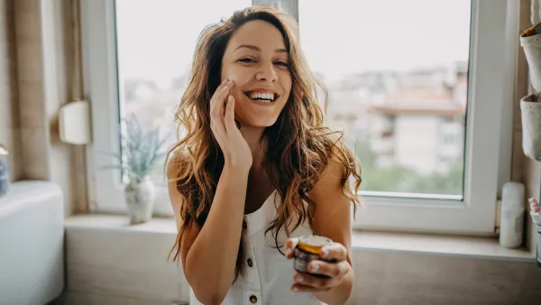 Young woman applies facial cream - stock photo
