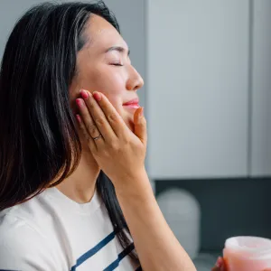 Portrait of a Beautiful Asian Woman Applying Face Cream - stock photo