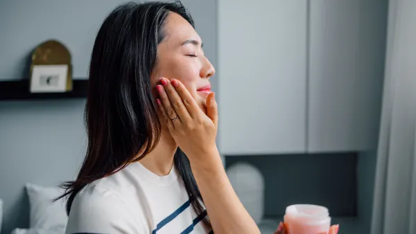 Portrait of a Beautiful Asian Woman Applying Face Cream - stock photo