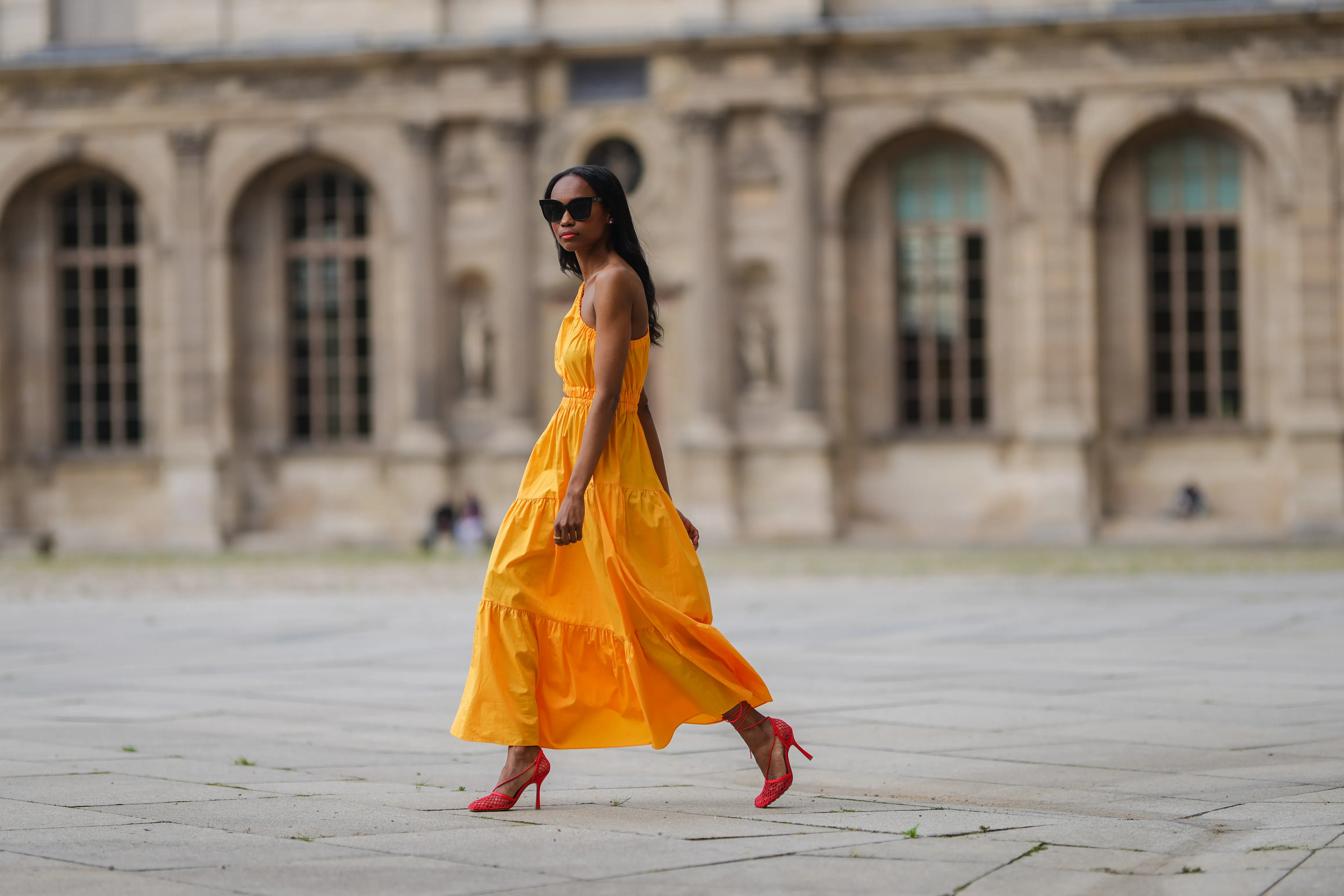 Emilie Joseph @in_fashionwetrust wears a yellow asymmetric cut-out midi dress from Mango, red mesh toe-cap strappy pumps heels shoes from Bottega Veneta, a gold ring, on June 05, 2021 in Paris, France.